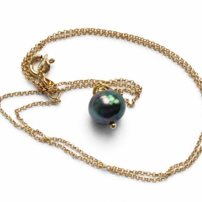 Colgante con cadena dorada y perla negra de Tahití sobre fondo blanco