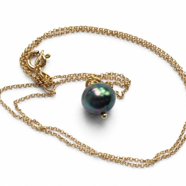 Colgante con cadena dorada y perla negra de Tahití sobre fondo blanco