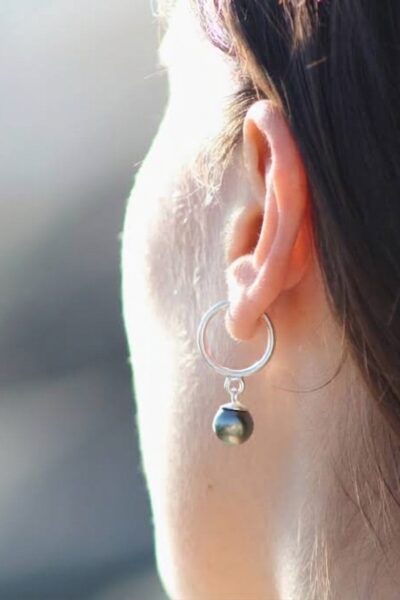 Mujer usando aros de plata con perla negra de Tahití